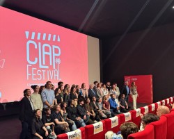 Groupe de participants posant sur scène devant un écran affichant “CLAP Festival”, dans une salle de cinéma avec des sièges rouges au premier plan.